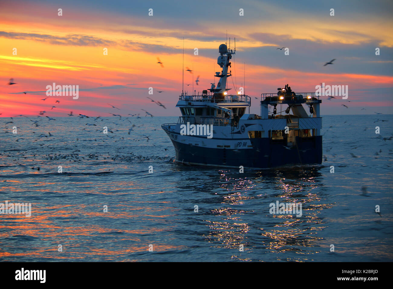 Fishing vessel 'Harvester' hauling fishing gear as sun sets over the North Sea. July 2014. Property released.  All non-editorial uses must be cleared individually. Stock Photo