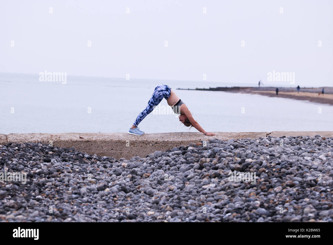Young Woman doing yoga on sea wall in Cromer, Norfolk, UK. Stock Photo