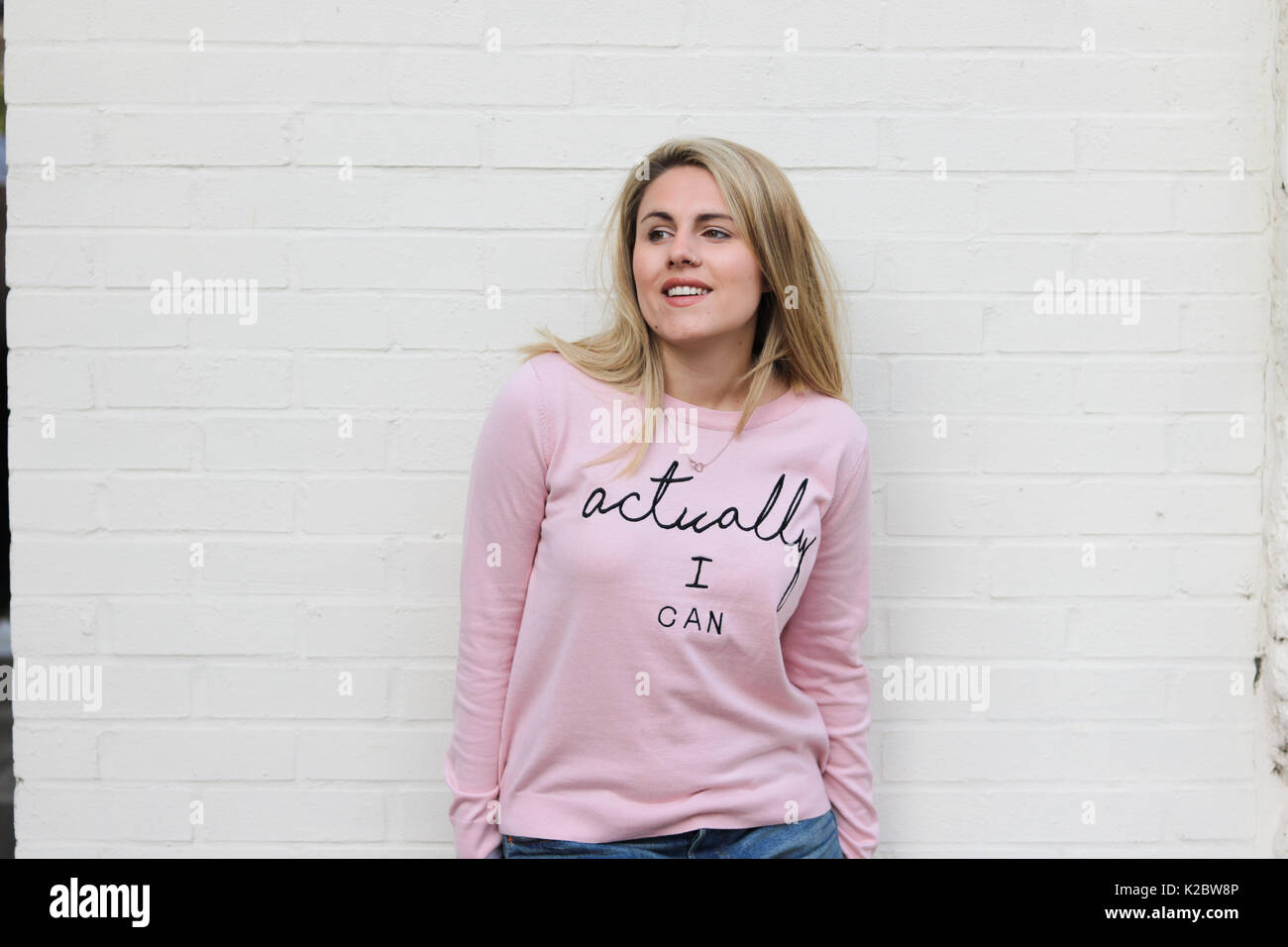 Young blonde woman in her early twenties wearing motivational jumper Stock Photo