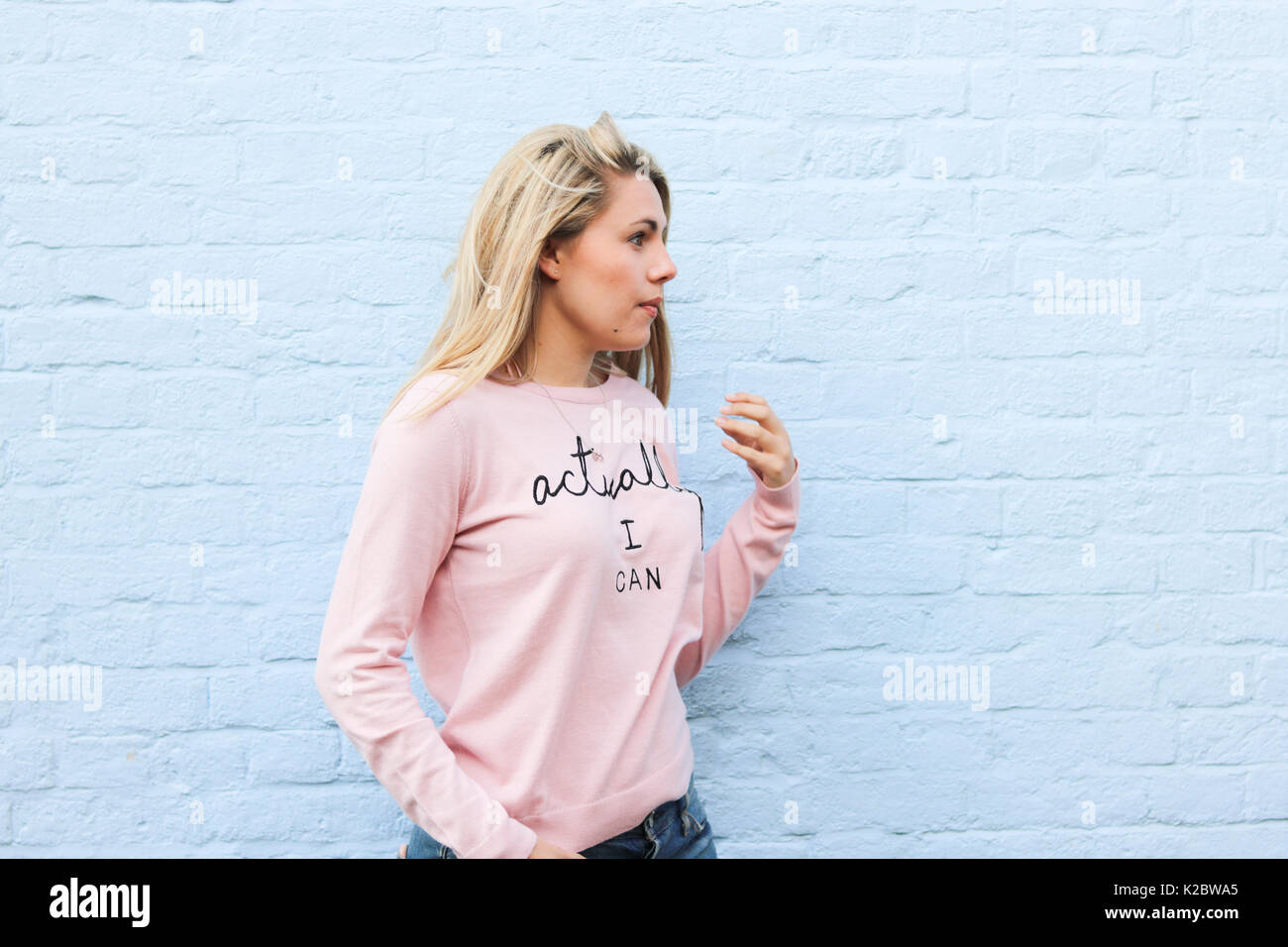 Young blonde woman in her early twenties wearing motivational jumper Stock Photo