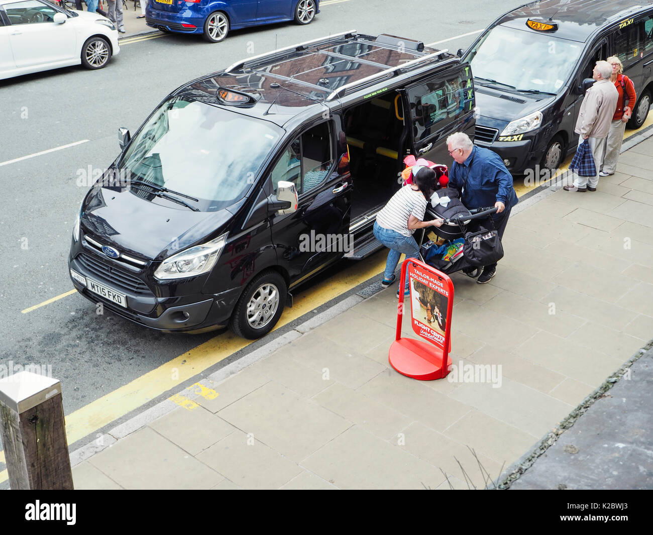 Loading a push chair into a taxi Stock Photo