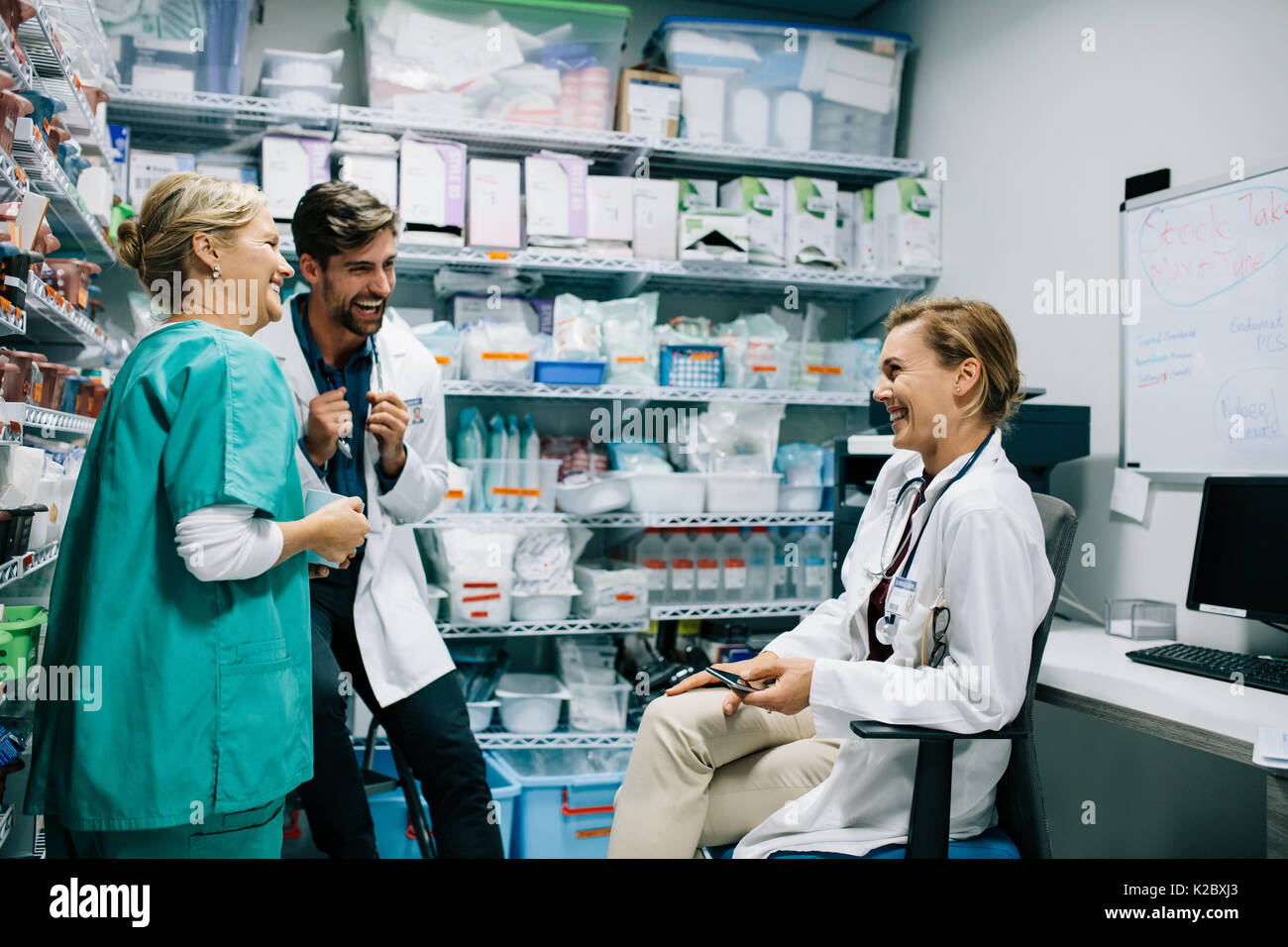 Hospital staff having casual discussion in the pharmacy. Three colleagues meeting in drugstore and laughing. Stock Photo