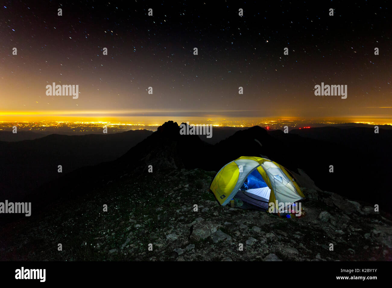 Campsite at night with city lit up  below, Three Fingers Lookout, Boulder River Wilderness, Mount Baker-Snoqualmie National Forest, Washington, USA. August 2014. Stock Photo