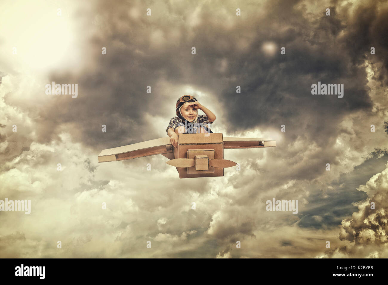 little kid fly with cardboard airplane in the sky Stock Photo