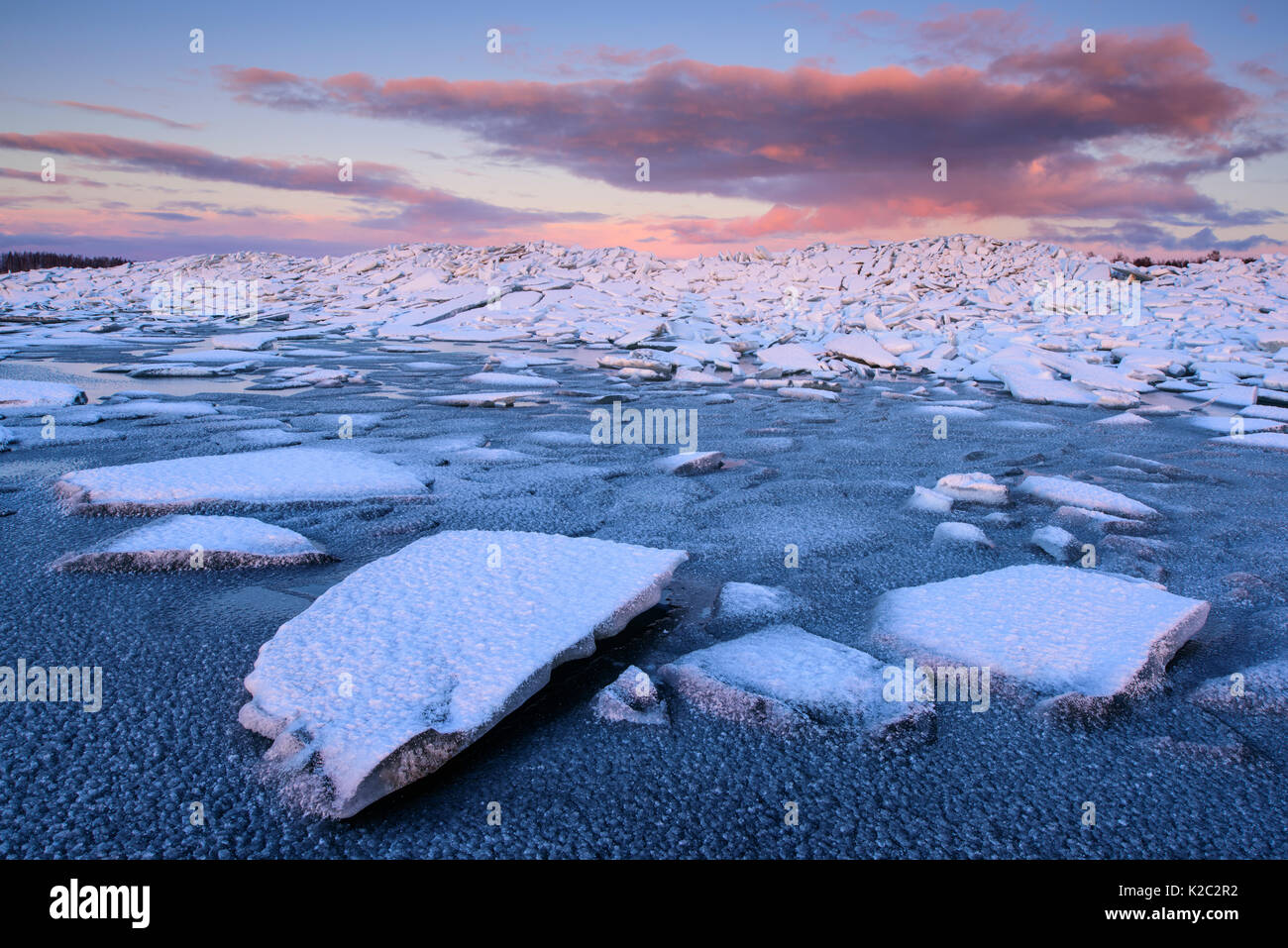 Broken ice covered in snow at sunset, on the shore of Lake Vortsjarv, gathered to shore by extreme winds, Estonia. December 2014. Stock Photo