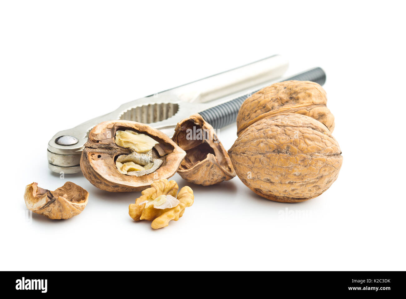 Cracked dried walnuts and nutcracker isolated on white background. Stock Photo