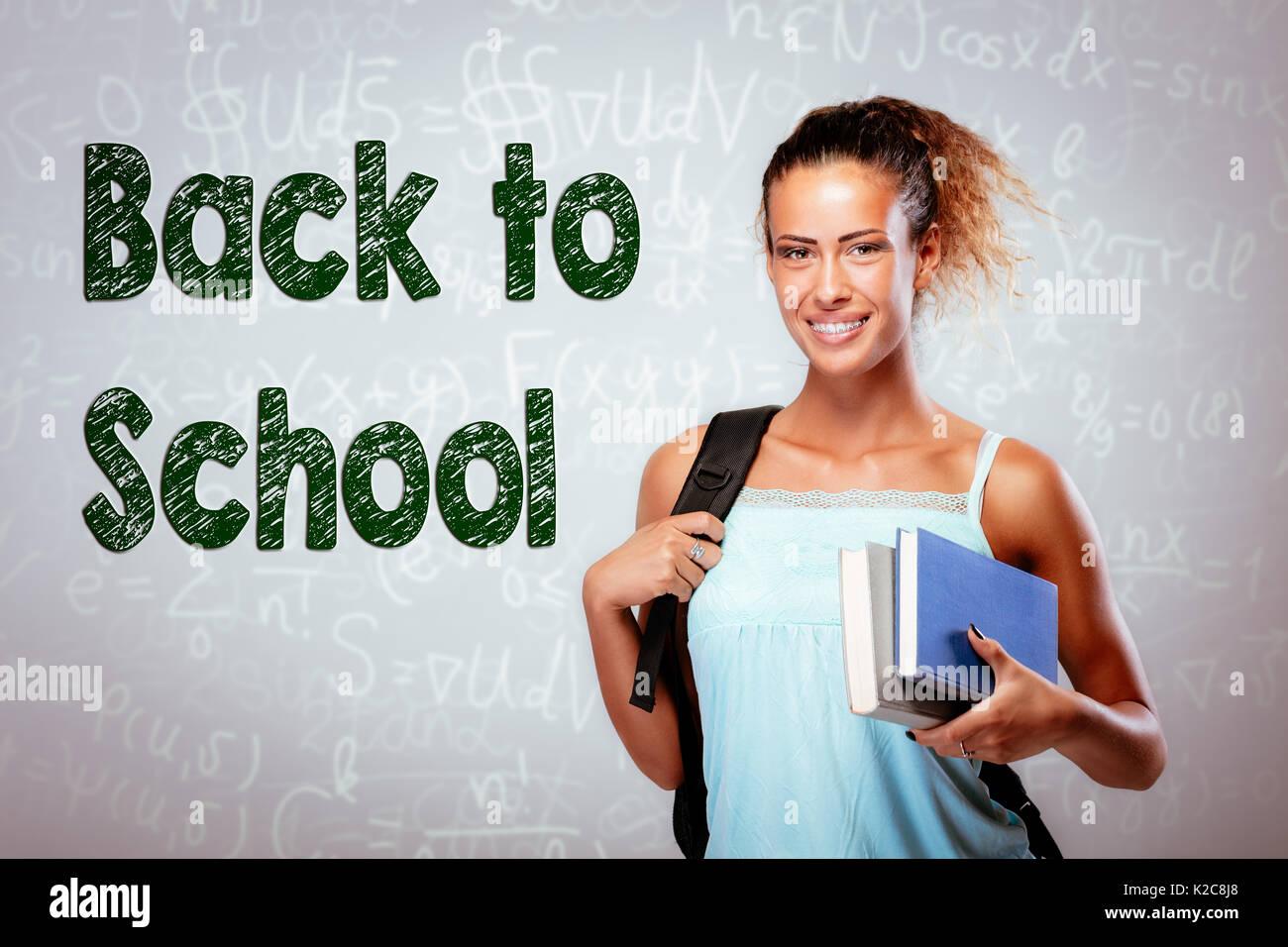 Beautiful smiling teenage girl with books and school bag. Looking at ...
