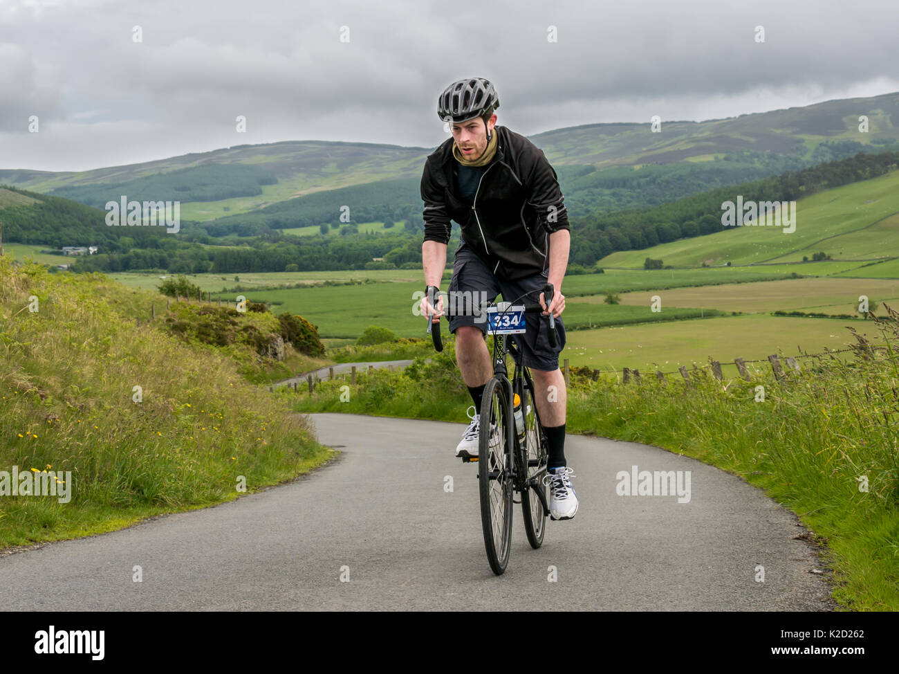 Young man on bike cycling up Dreva Hill, Cycle Law Scotland Skinny Tweed 2017 cycling event, Peebles, Scottish Borders, Scotland, UK Stock Photo