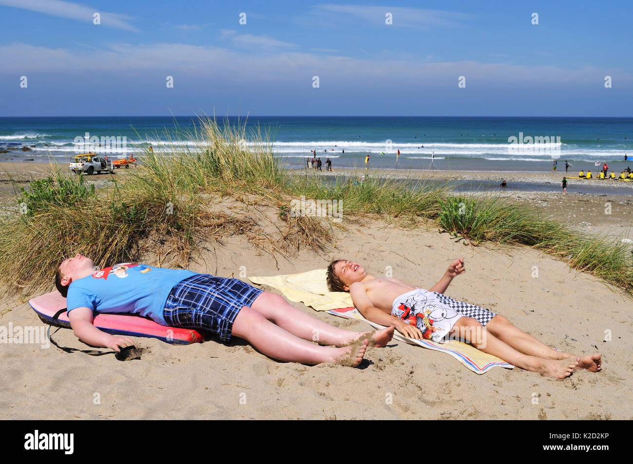 two teenage boys sunbathing in the sand dunes on porthtowan beach