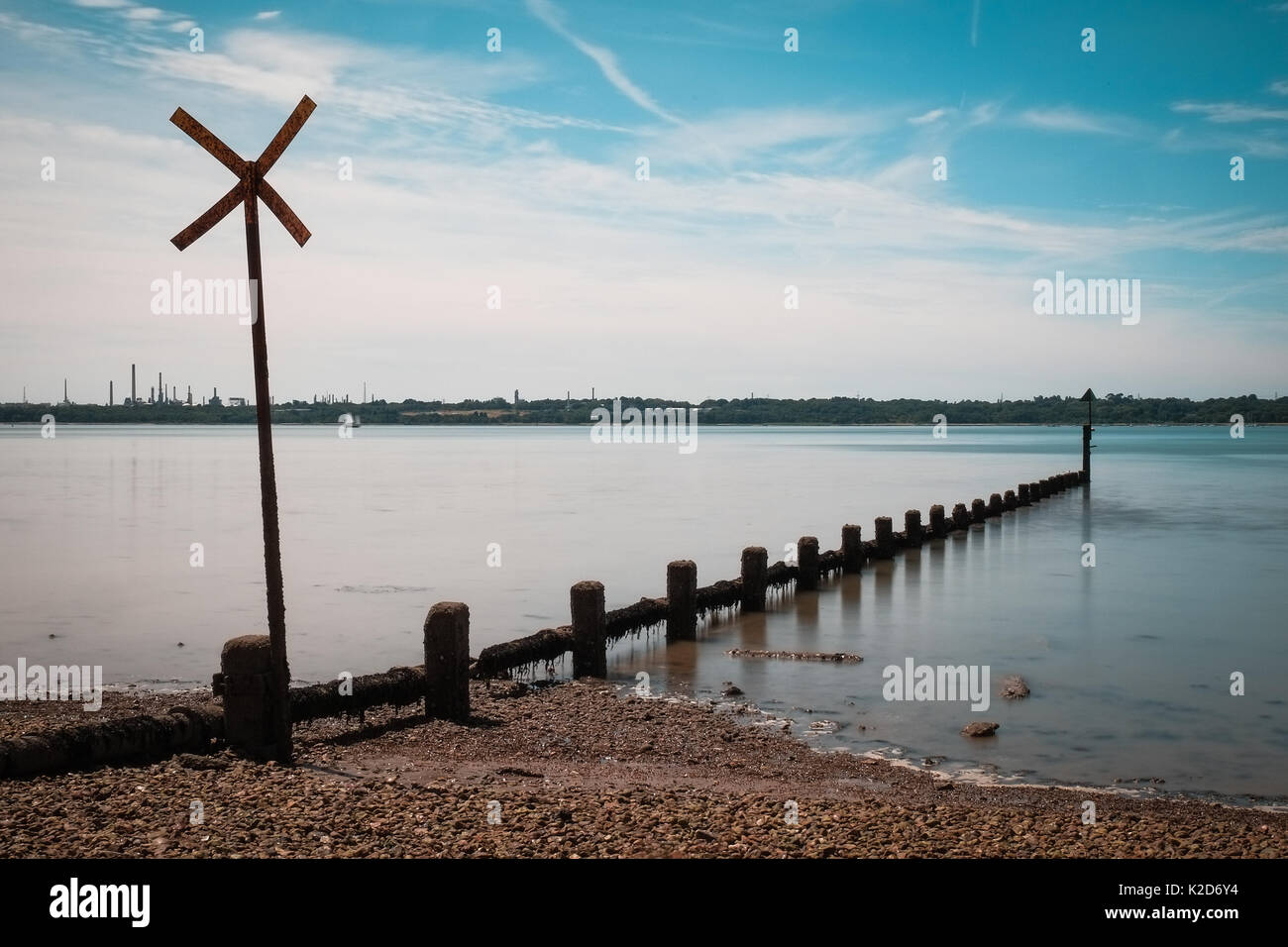 Wooden groynes stretch out into a glassy sea at Weston Shore, Southampton Stock Photo