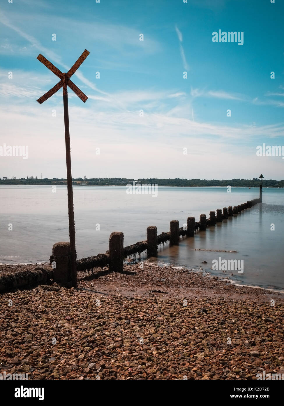 Wooden groynes stretch out into a glassy sea at Weston Shore, Southampton Stock Photo