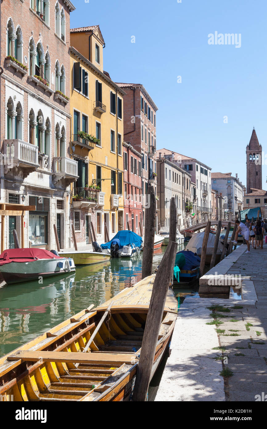 View along Rio de San Barnaba, Dorsoduro, Venice, Italy towards the bell tower of Chiesa San Barnaba with an old colorful yellow wooden boat in the fo Stock Photo