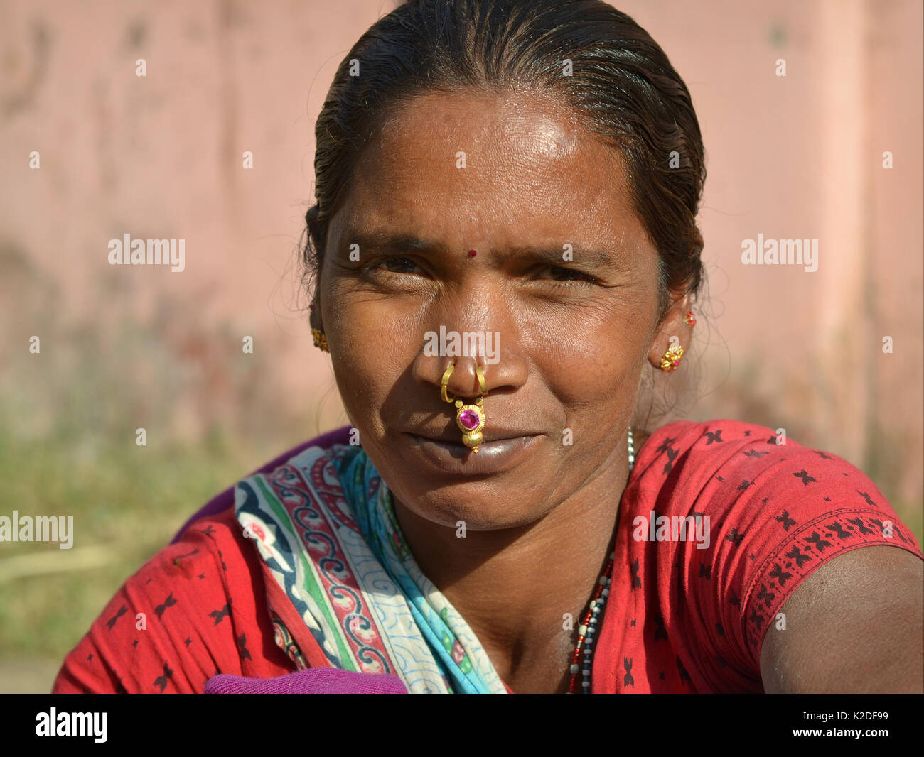 Young Indian Adivasi woman (Desia Kondh tribe aka Kuvi Kondh tribe) with gold-and-gemstone tribal nose jewellery smiles for the camera. Stock Photo