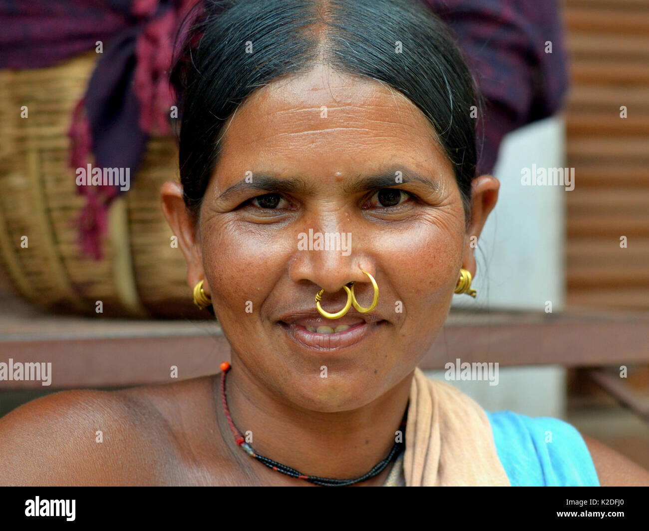 Indian Adivasi woman (Mali tribe) with two golden nose rings and distinctive tribal earrings smiles for the camera. Stock Photo