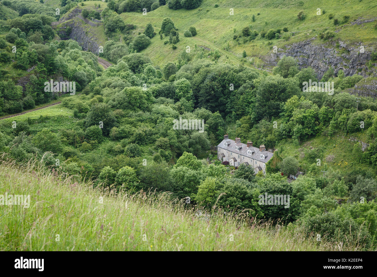Railway cottages, Chee Dale, Peak District National Park, Derbyshire, UK. Quarried limestone rockfaces can be seen along the ridge above. Stock Photo