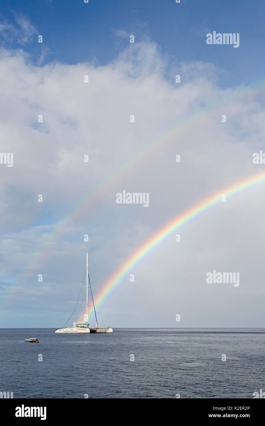 Sailing boat and rainbow near the coast of Dominica, Caribbean Sea, Atlantic Ocean. Stock Photo
