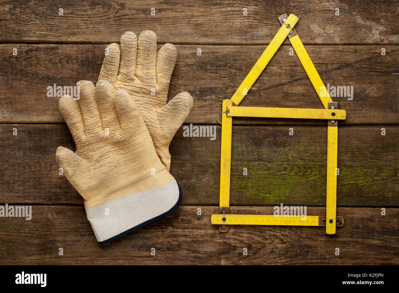 Yellow meter tool with pair of working gloves on vintage wooden background . Stock Photo