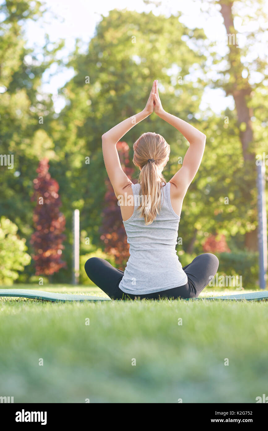 Young woman practicing yoga outdoors at the park Stock Photo