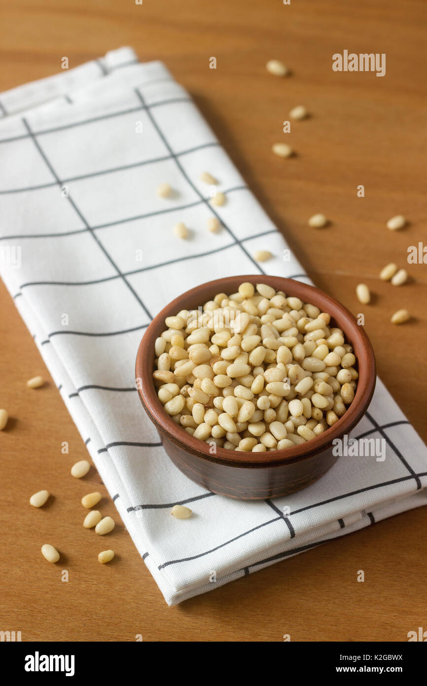 Pine nuts in a clay bowl on a wooden table Stock Photo