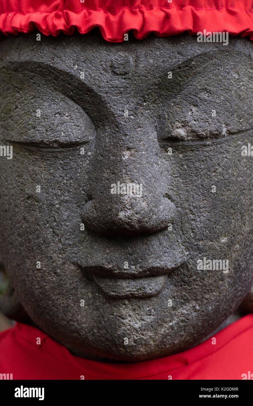 Tokyo, Japan, Buddhist stone statue face wearing a red hat Stock Photo