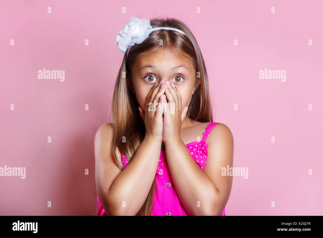 Surprised smiling little girl in pink dress Stock Photo - Alamy