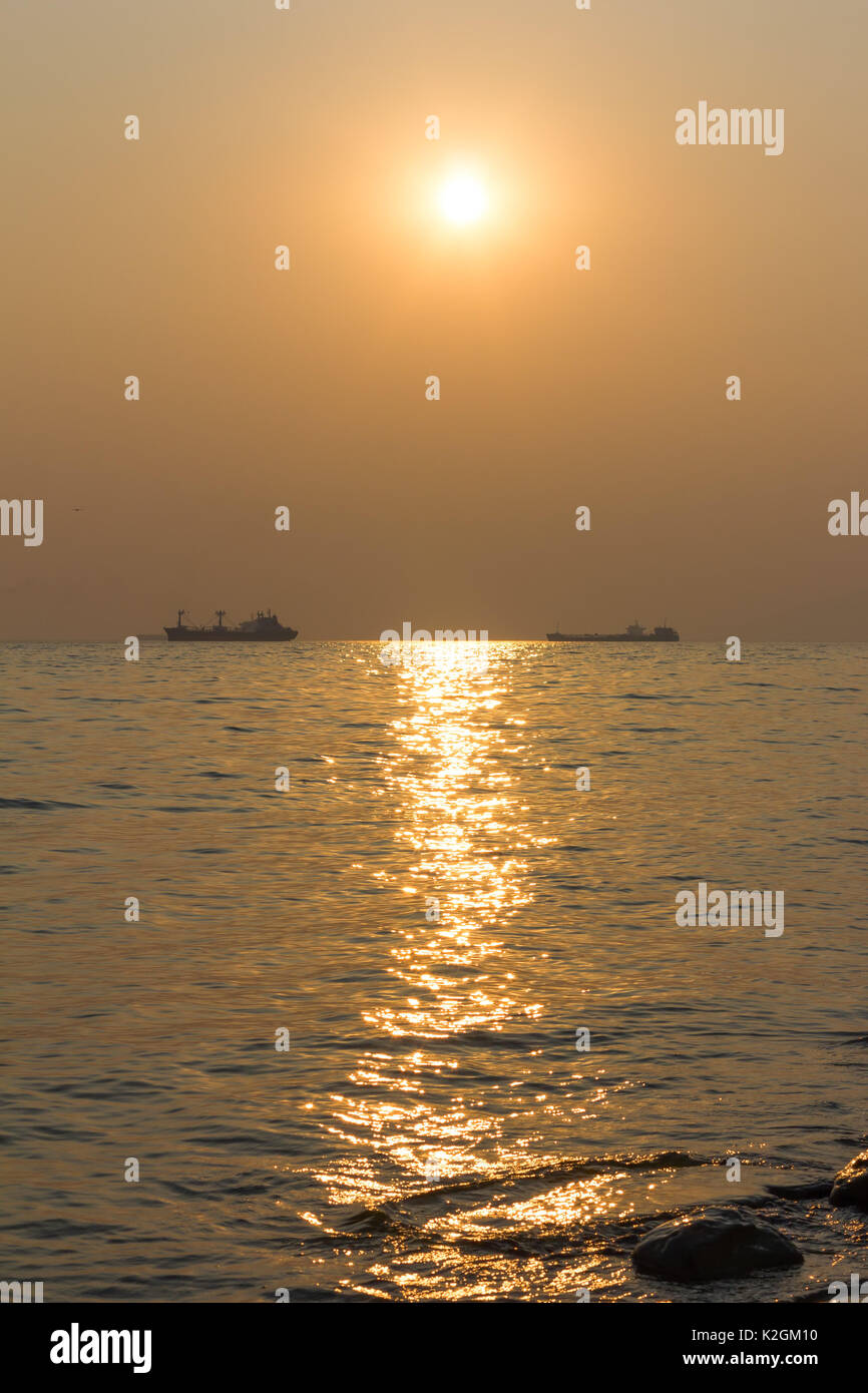 ships at sea on the horizon at sunset Stock Photo - Alamy