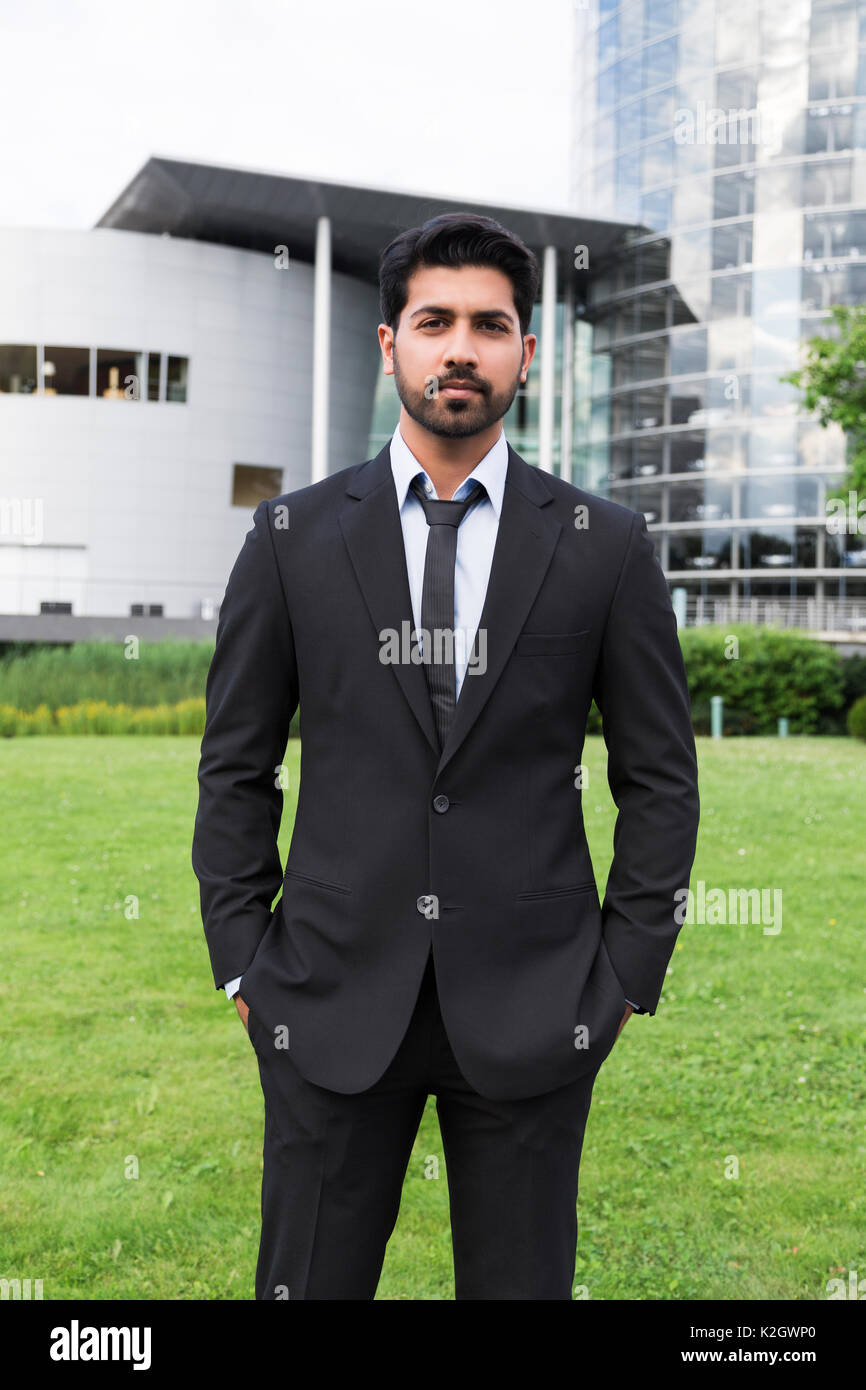 Arabic eastern indian serious businessman or worker in black suit with tie  and shirt with beard standing in front of an office building with hands in  Stock Photo - Alamy