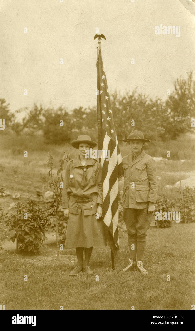 Antique c1930 photograph, Girl Scout and Boy Scout with American flag. The boy is wearing Converse sneakers. SOURCE: ORIGINAL PHOTOGRAPH. Stock Photo