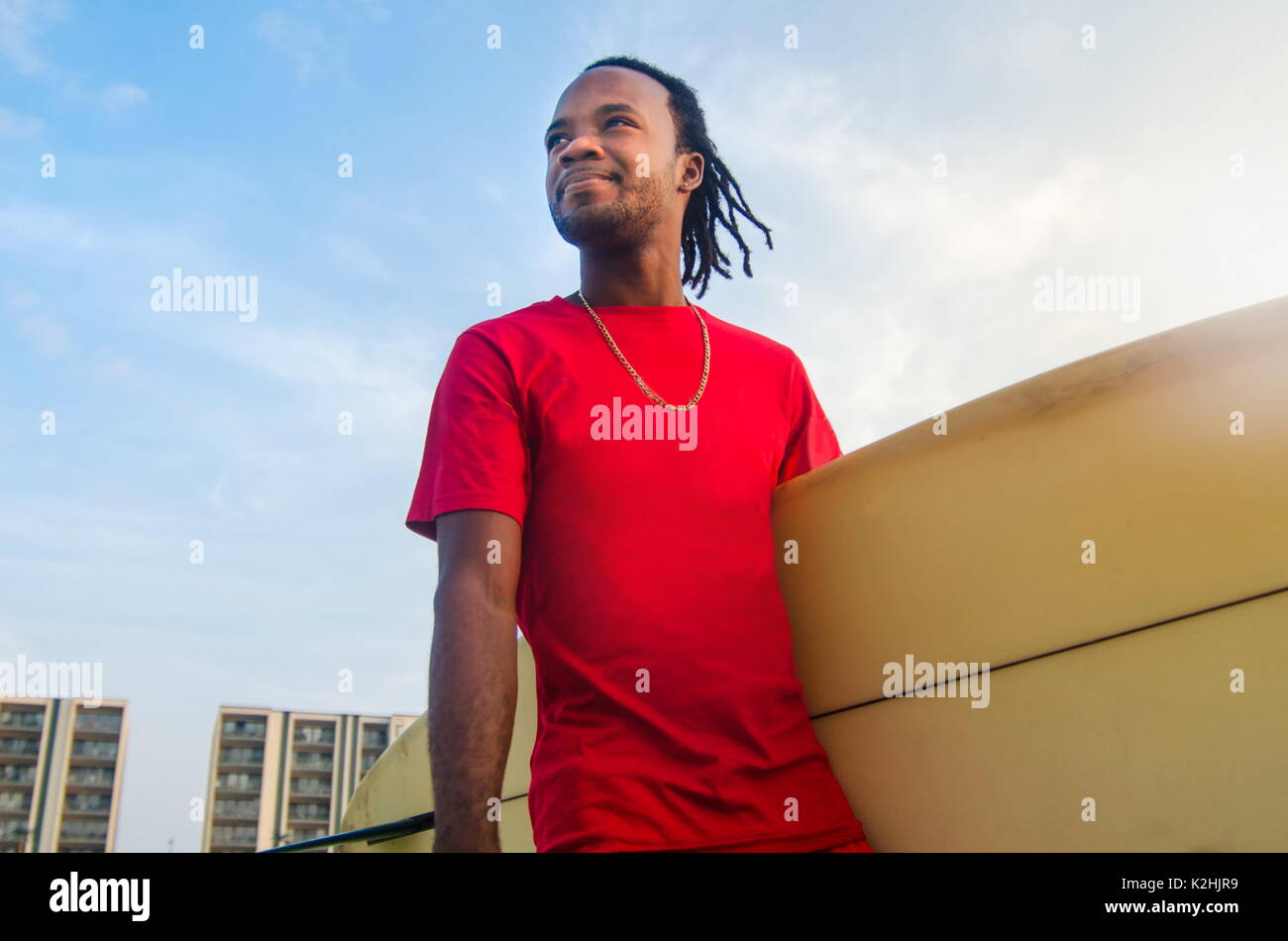 Young African American man holding a surfboard outdoors Stock Photo