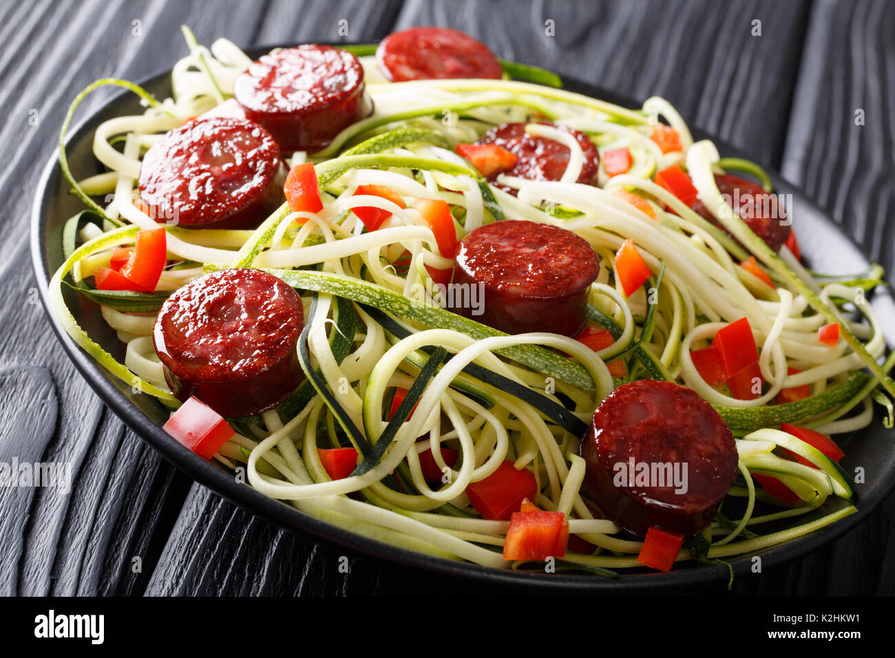 Pasta of green zucchini with red pepper and grilled sausages close-up on the table. horizontal Stock Photo