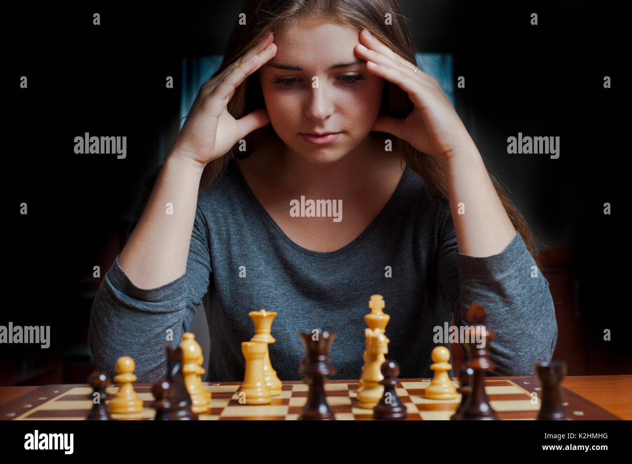 Woman playing chess thinking of next move Stock Photo - Alamy