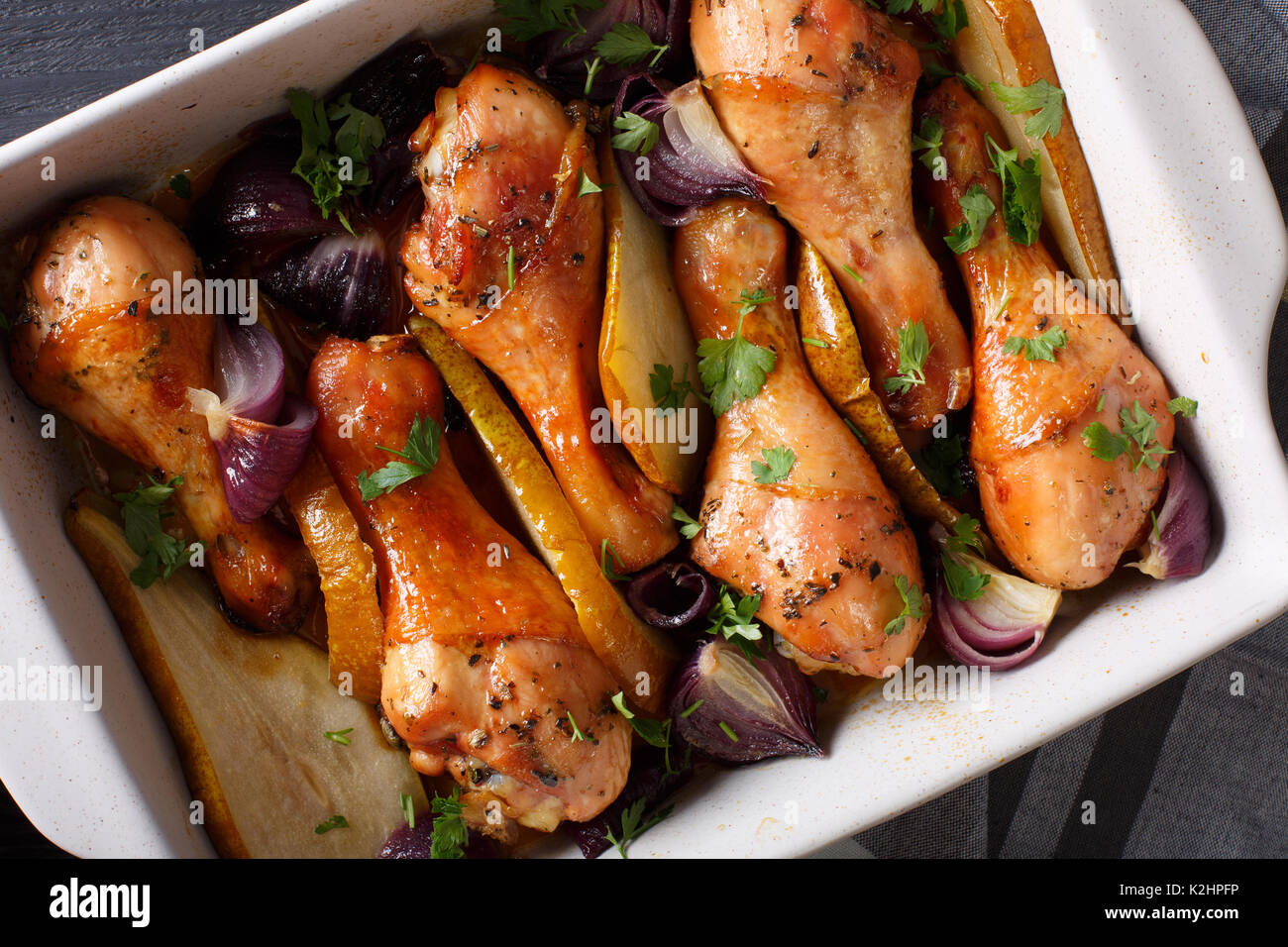 Chicken legs baked with red onions and greens in honeysoy sauce close