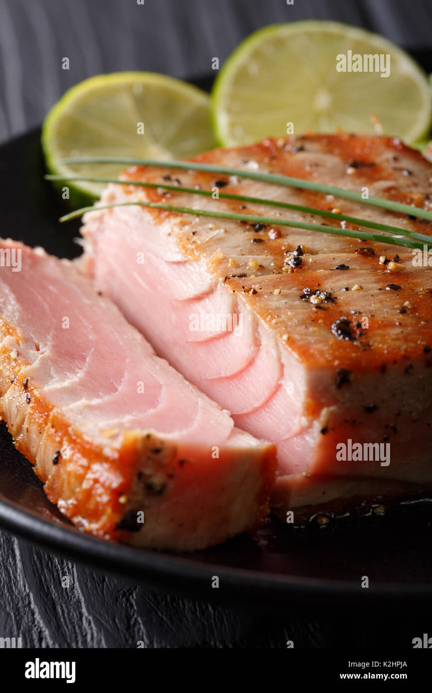 grilled peppers seared Tuna steak with lime macro on a plate. vertical