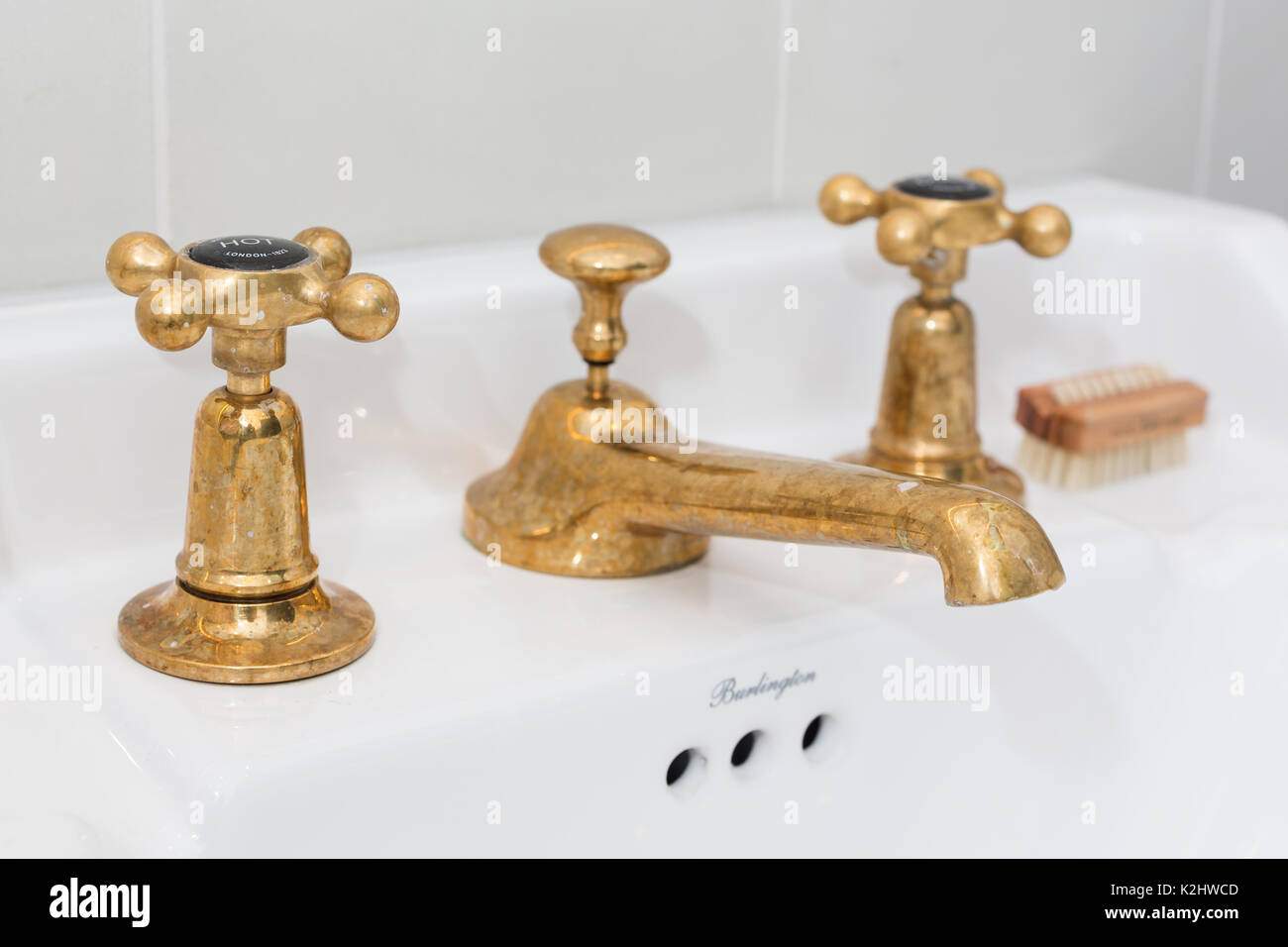 Brass basin taps in white bathroom Stock Photo