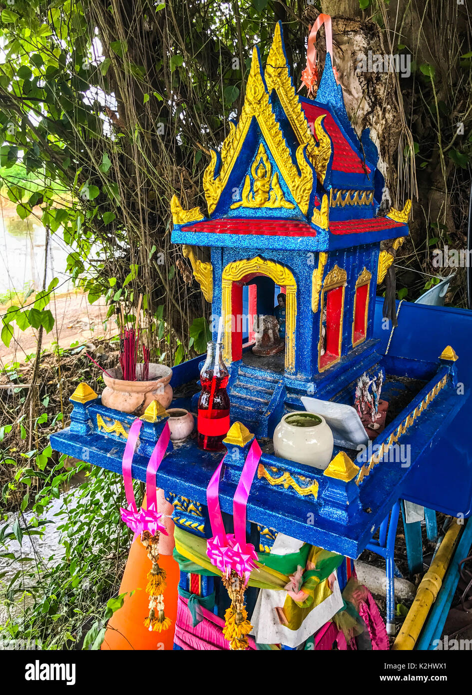 Colorful Traditional Thai outdoor spirit house shrine with flower Stock