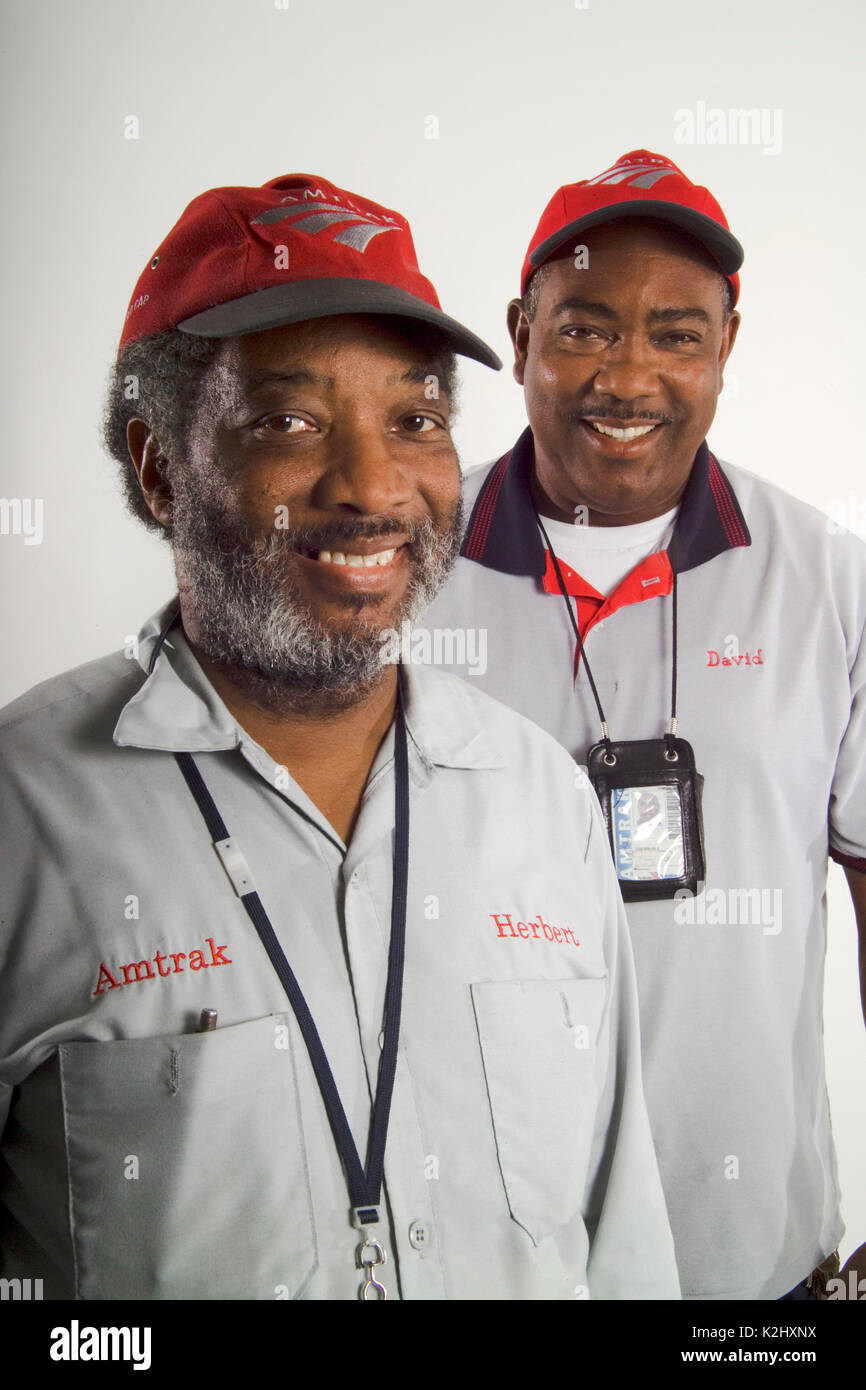 Two African American Red Cap porters pose at Union Station in Los Angeles. Note uniforms and