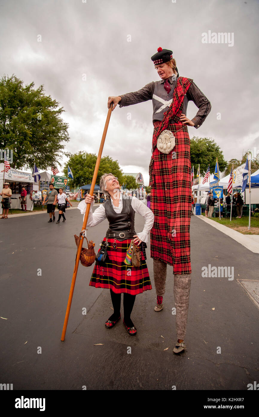 Wearing a colorful tartan, a Scotsman with bonnet and kilt on stilts gets some admiration from a costumed lady at a Scottish festival in Costa Mesa, CA. Stock Photo