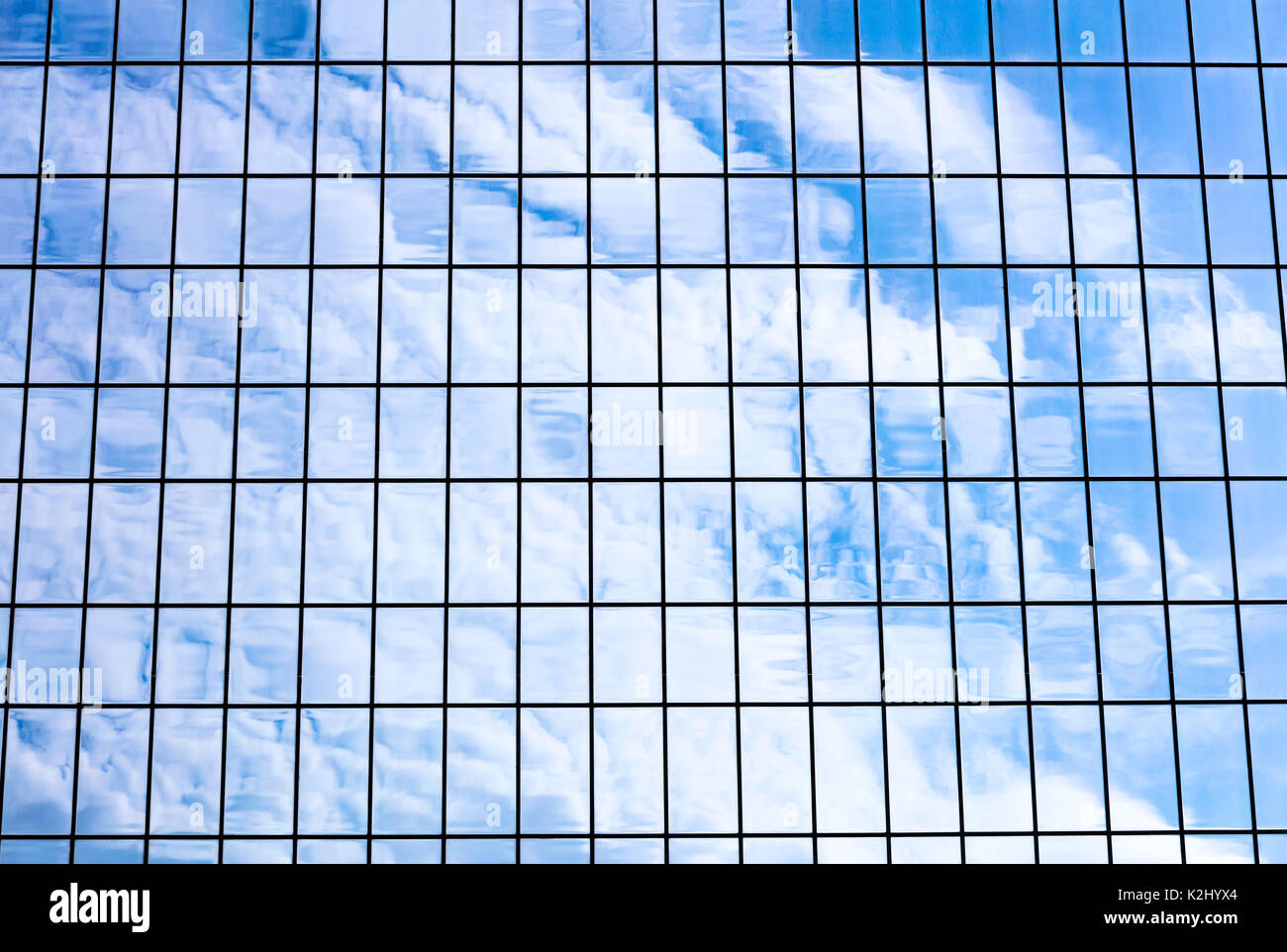 sky and clouds reflected in office glass building facade. modern ...