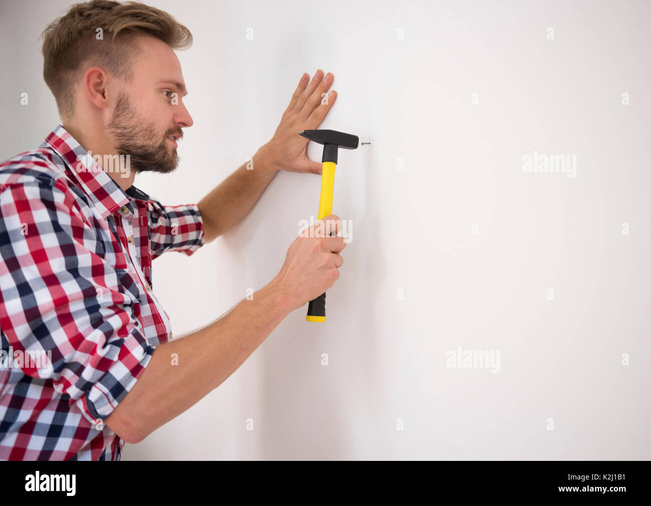 гвоздь вбитый в стену. забивание гвоздя. вбить молотком в стену. держатель для забивания гвоздей. вбить молотком в стену.