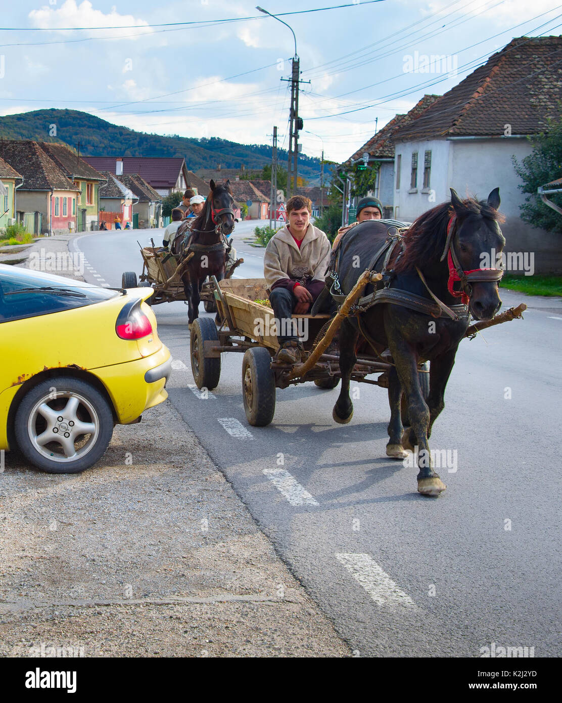 DANES, ROMANIA - OCTOBER 05, 2016: Locals driving horse cart on a road in a small Romanian village. The Romanian government claims that 10% of road ac Stock Photo