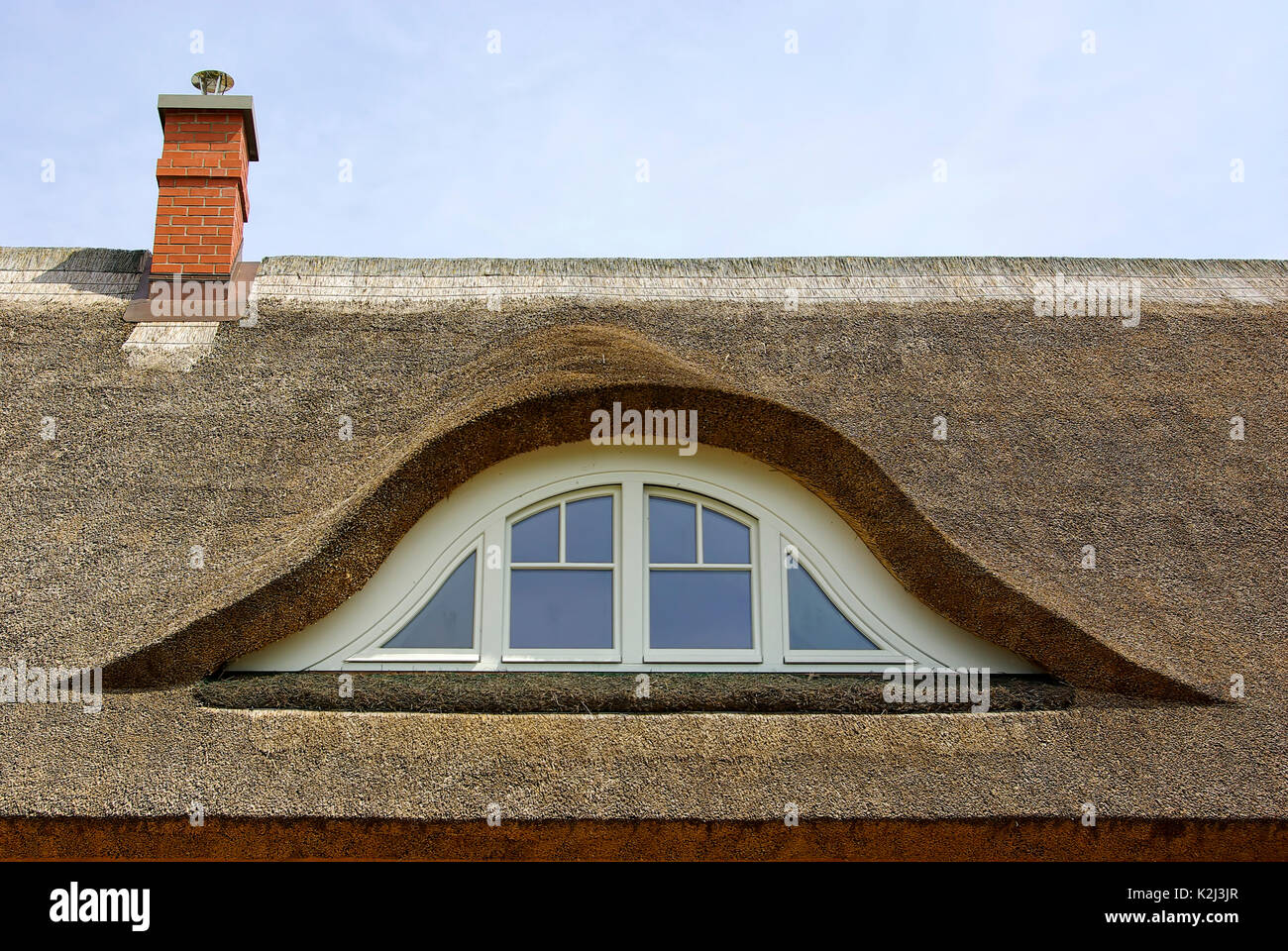 A reed roof with an eyebrow dormer on top of a typical dwelling-house as being usual in Northern Germany and Mecklenburg-Pomerania. Stock Photo