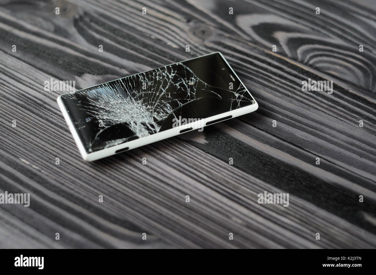 Smartphone with broken screen on dark wooden background Stock Photo
