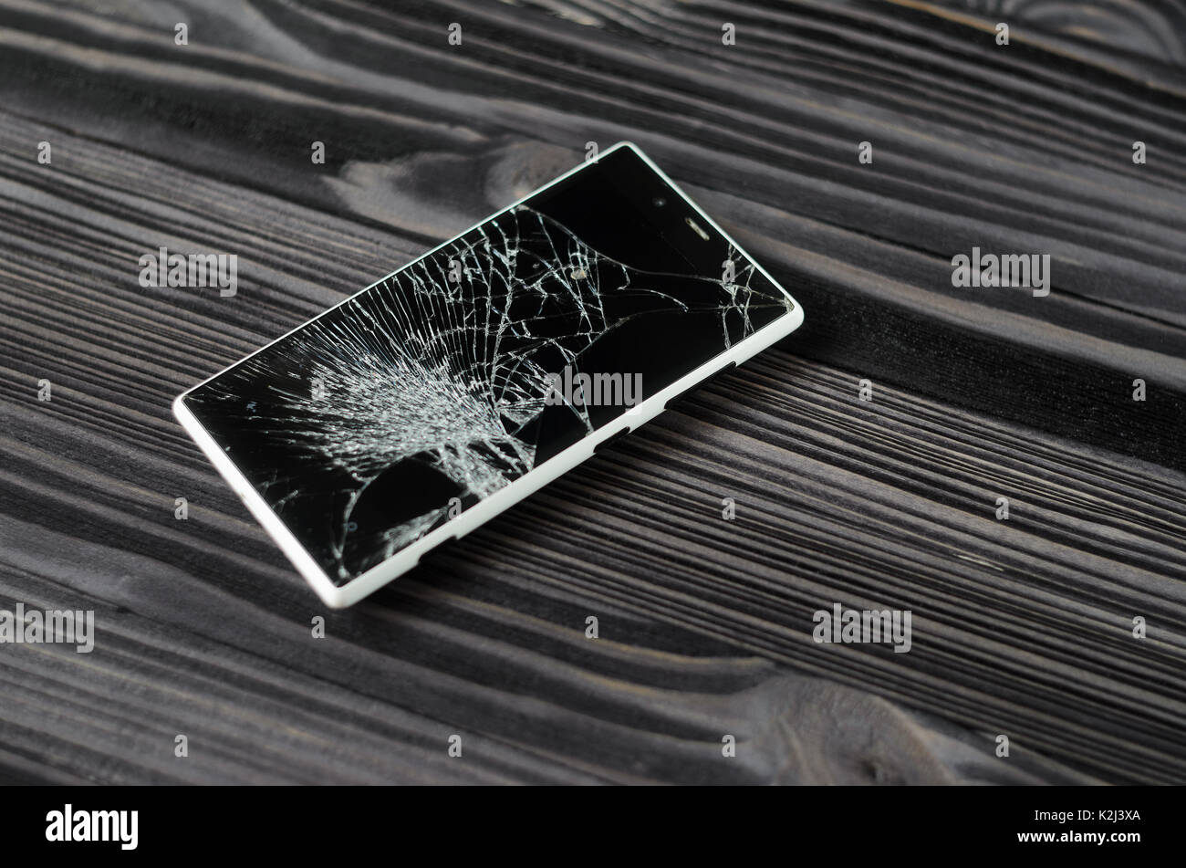 Smartphone with broken screen on dark wooden background Stock Photo
