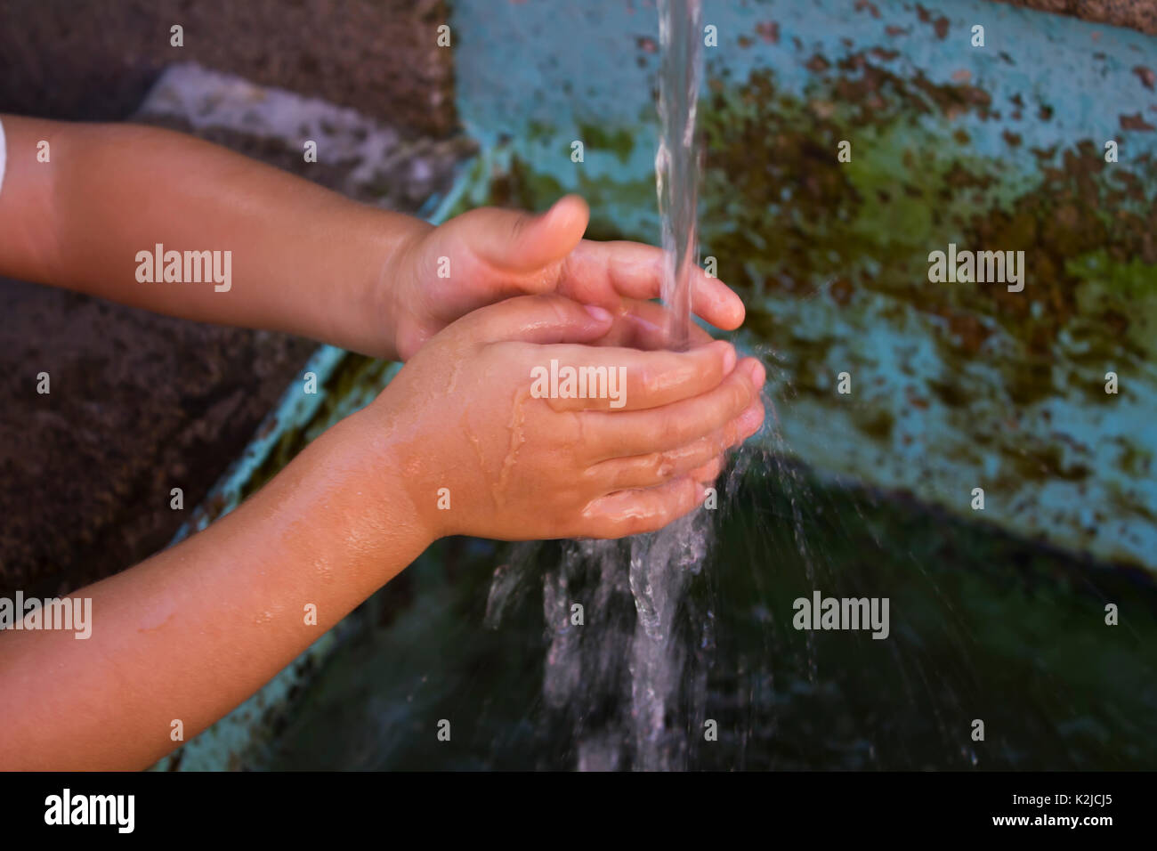 kid washing hand in public water fountain Stock Photo