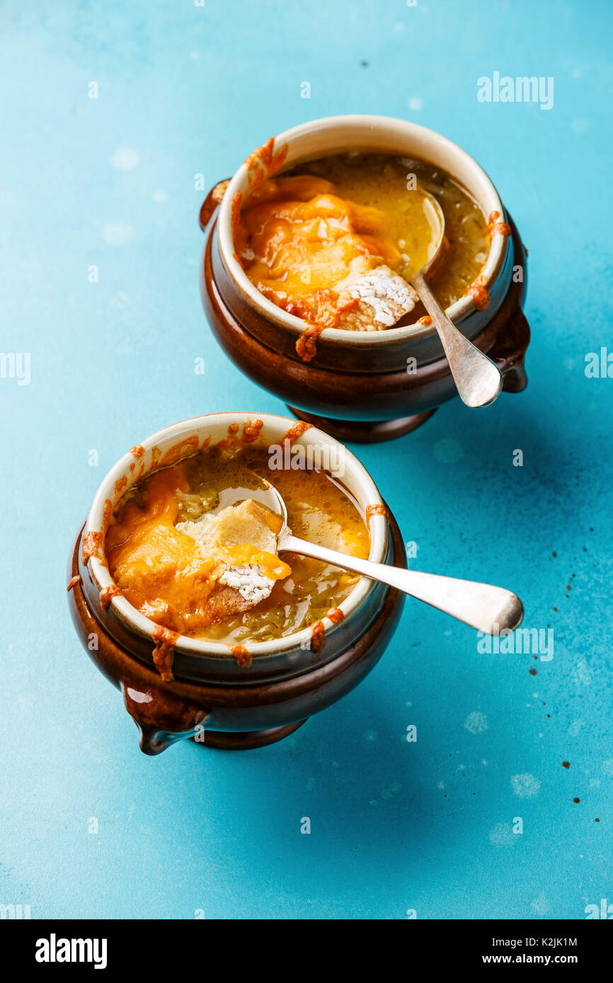 Authentic French Onion soup with dried bread and cheddar cheese in bowl on blue background Stock