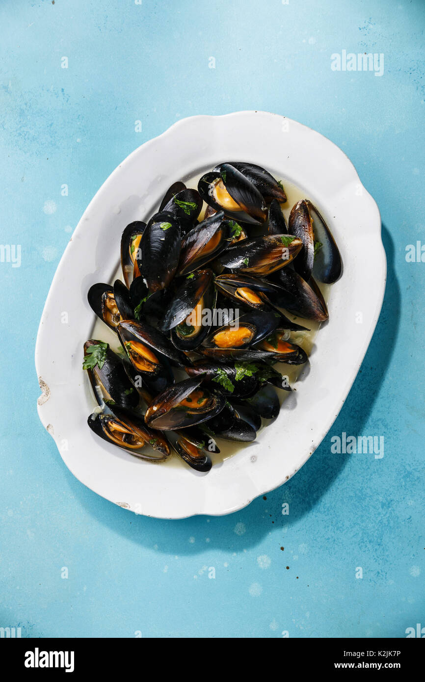 Mussels on white plate on blue background Stock Photo