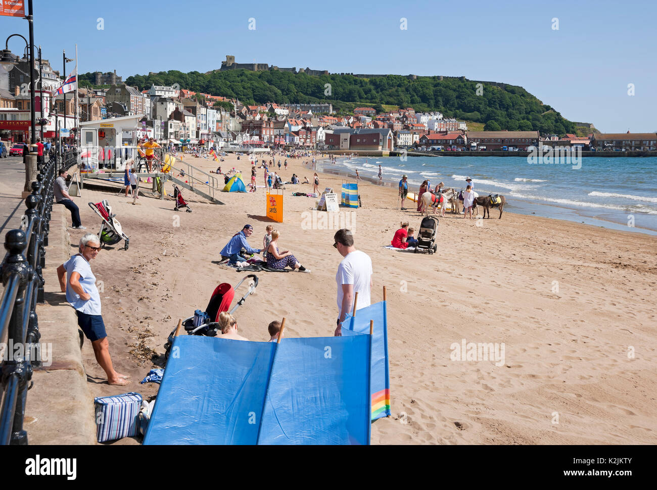 People visitors tourists and RNLI lifeguard station on the beach in summer South Bay Scarborough seaside North Yorkshire England UK Great Britain Stock Photo