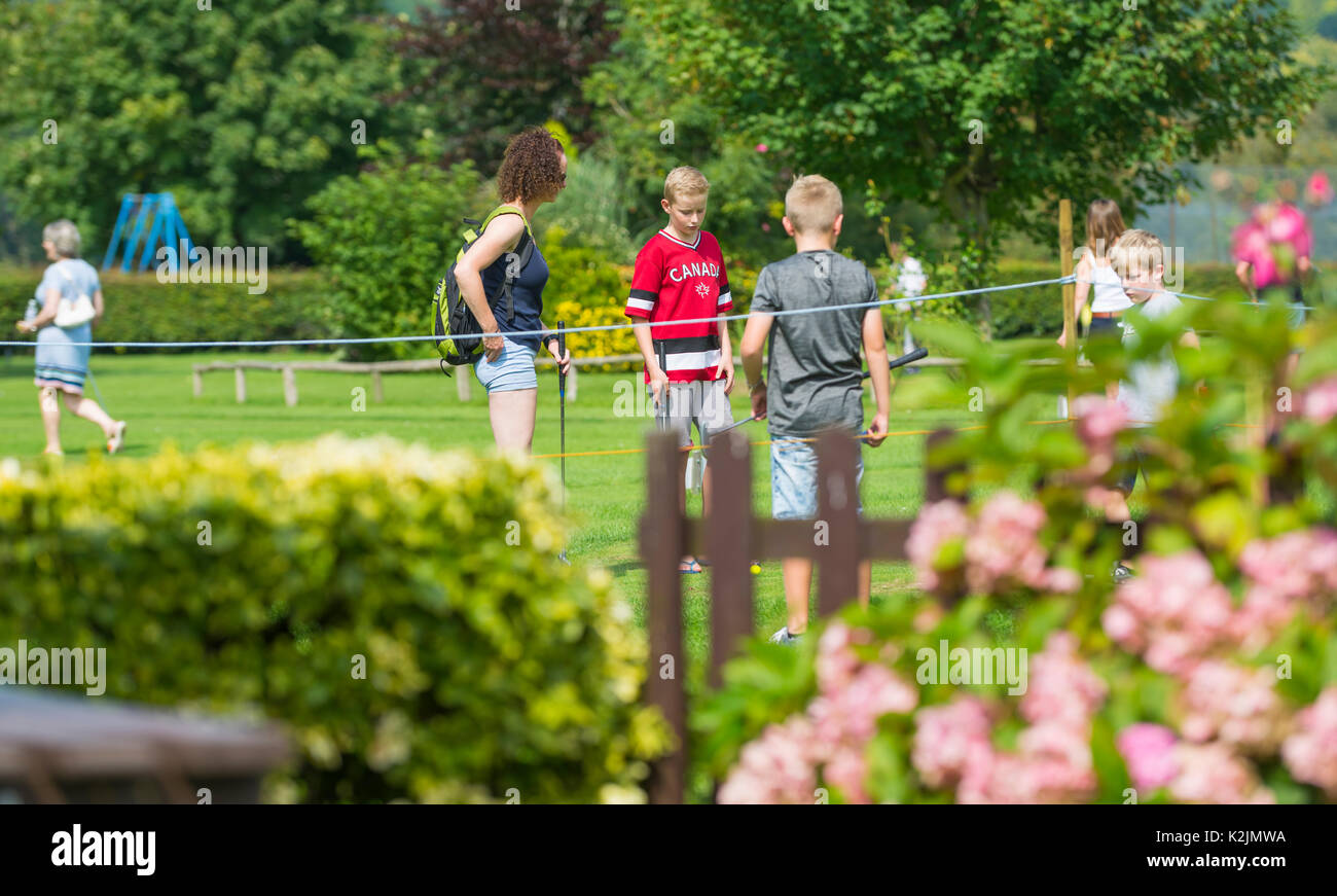 Children playing putting on a small putting course in Summer in the UK. Summer holiday concept. Summer holidays concept. Stock Photo