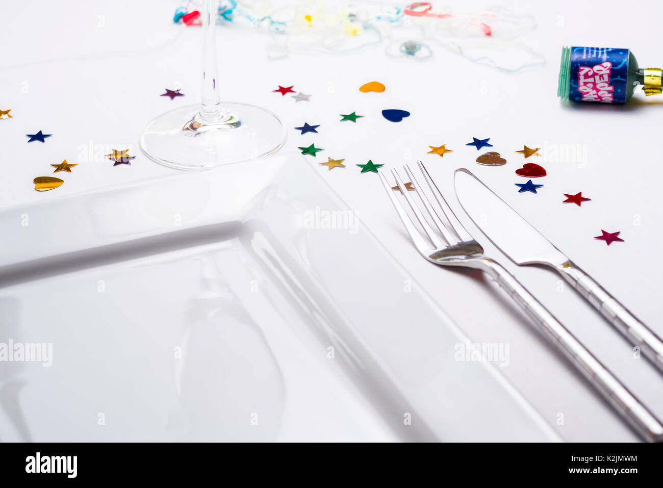 Single place table setting, knife fork plate, with decoration confetti. Stock Photo