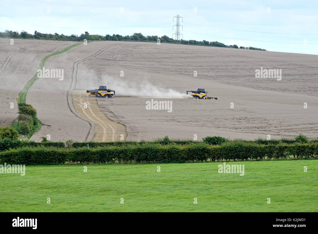 Combined harvesters working in field On White Hill Kingsclere Hampshire UK Stock Photo